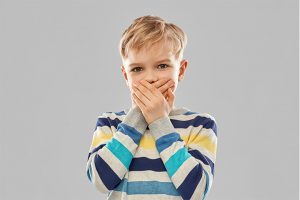 Un niño se tapa la boca porque tiene halitosis